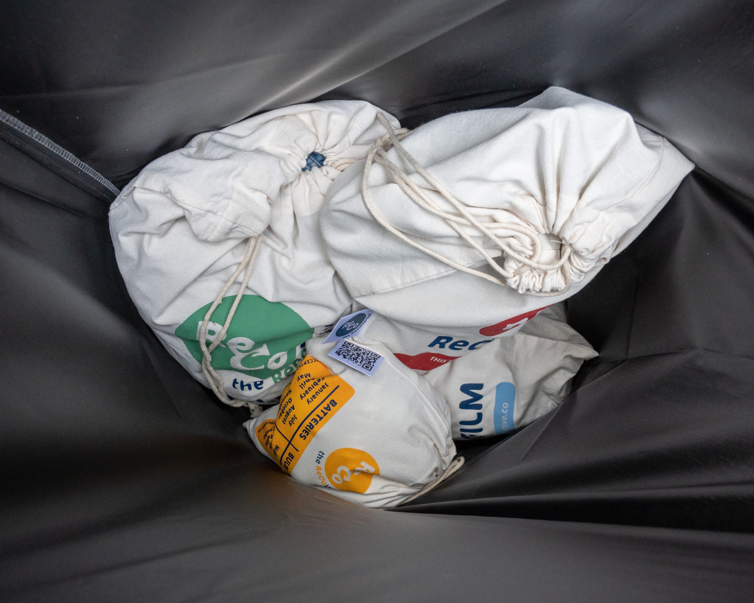 Labeled ReCollective canvas bags placed inside the black waterproof pickup bag