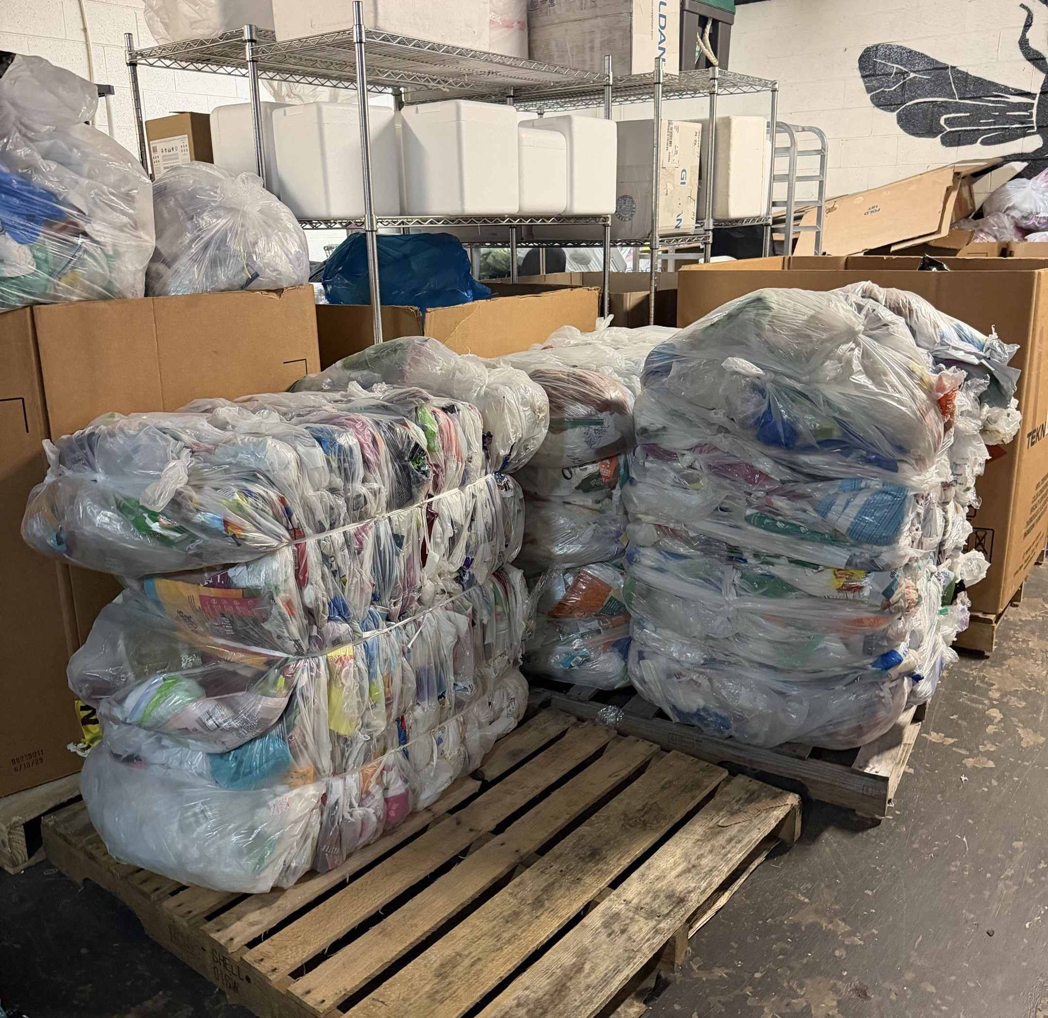 Bales of Crinkly Packaging stacked on pallets at The ReCollective warehouse